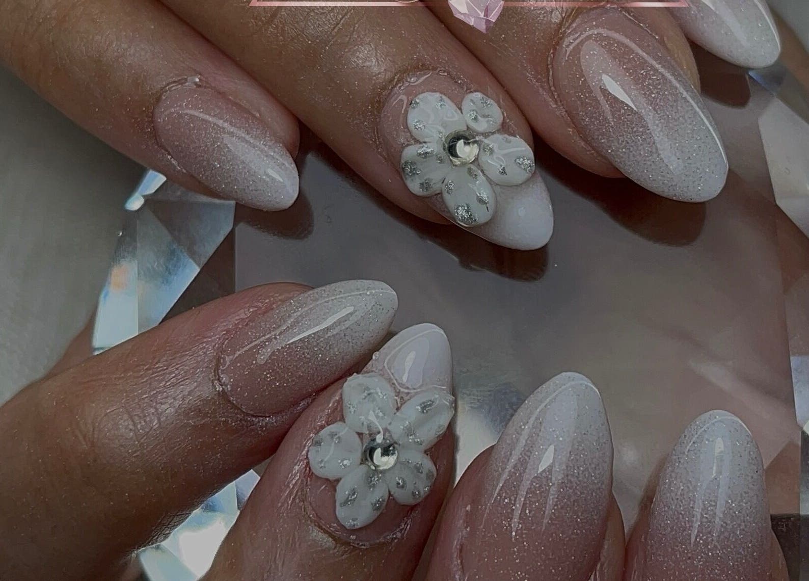 Manucure incrustée de fleurs blanches à Vannails Art Studio, Thil, Occitanie, FR.