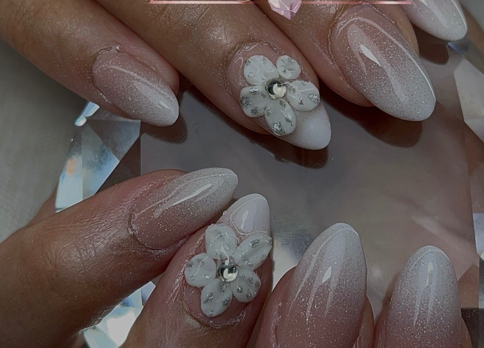 Manucure incrustée de fleurs blanches à Vannails Art Studio, Thil, Occitanie, FR.