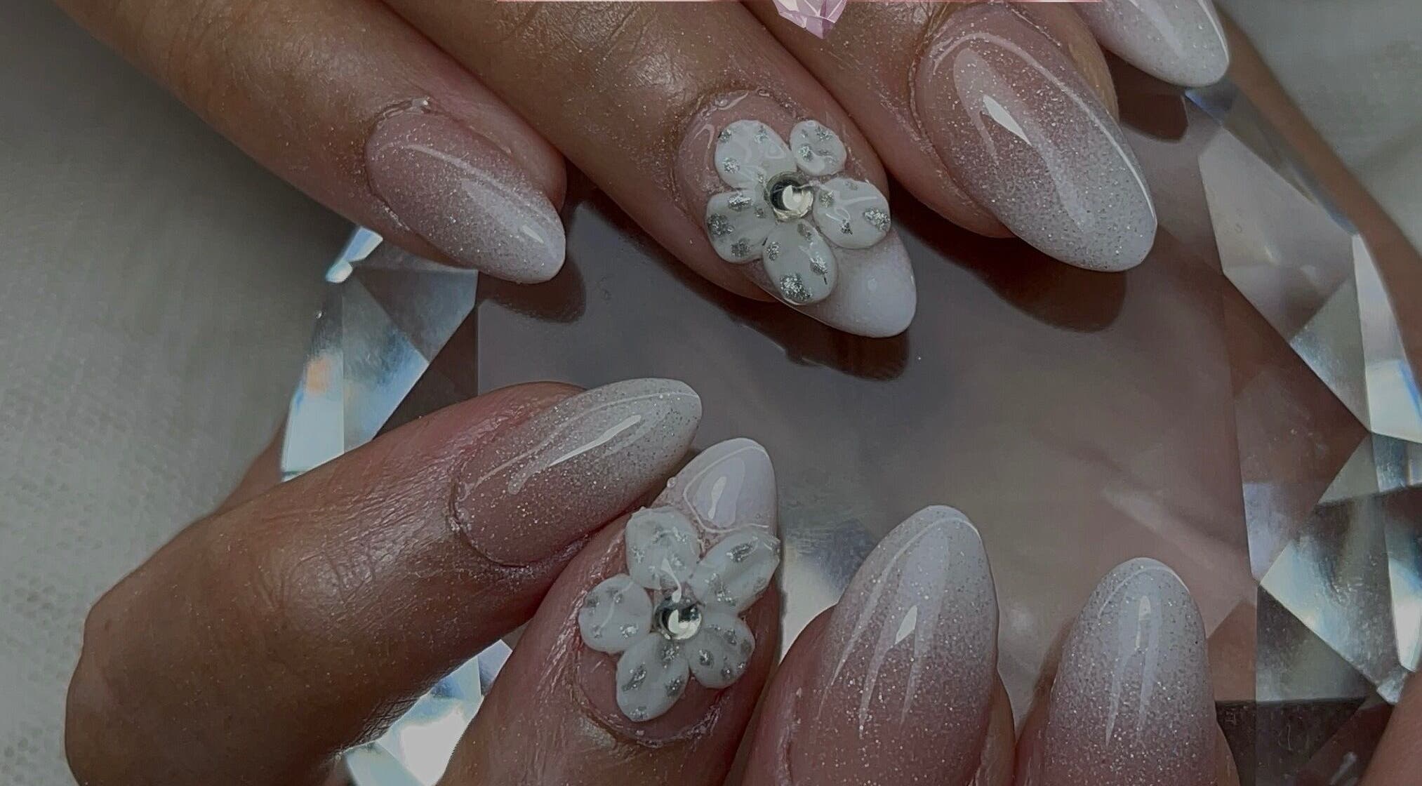 Manucure incrustée de fleurs blanches à Vannails Art Studio, Thil, Occitanie, FR.