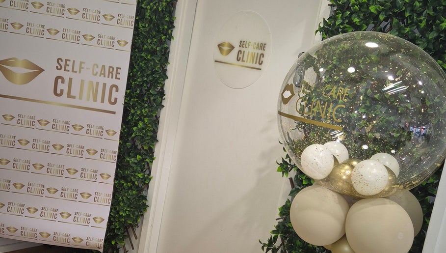 Stylish entrance at Self Care Clinic, Porth, Wales, GB, featuring elegant decor and gold-themed balloons.