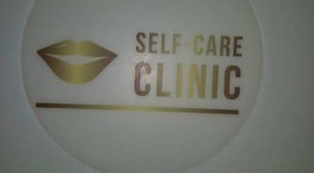 Self Care Clinic logo in gold with lips icon at Porth, Wales, GB.