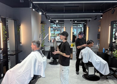 Stylish interior of Barbers Of Belgium Pty Ltd., Southport QLD, AU with barbers attending clients.