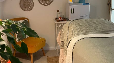 Calming room at The Holistic Hideaway, Pott Row, England, GB with cozy chair and massage bed.