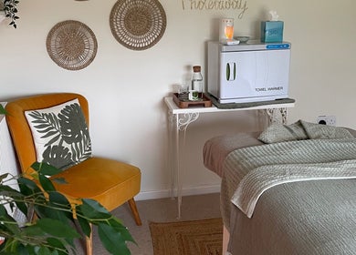 Tranquil therapy room at The Holistic Hideaway, Pott Row, England, with a cozy chair and a towel warmer.