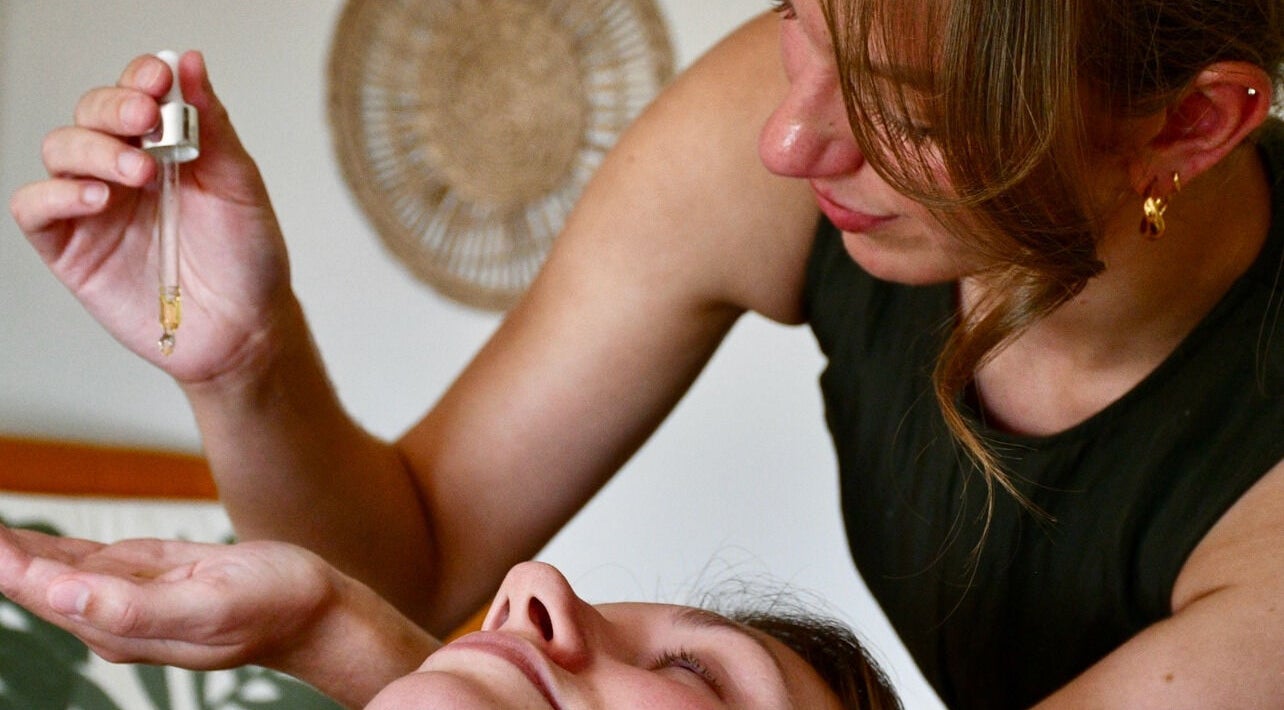 Therapist applying essential oil at The Holistic Hideaway, Pott Row, England, GB for soothing relaxation.