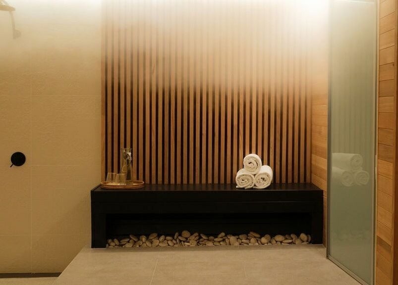 Elegant spa interior at Chimes Day Spa in Denmark, Western Australia, AU, featuring wood accents and rolled towels.