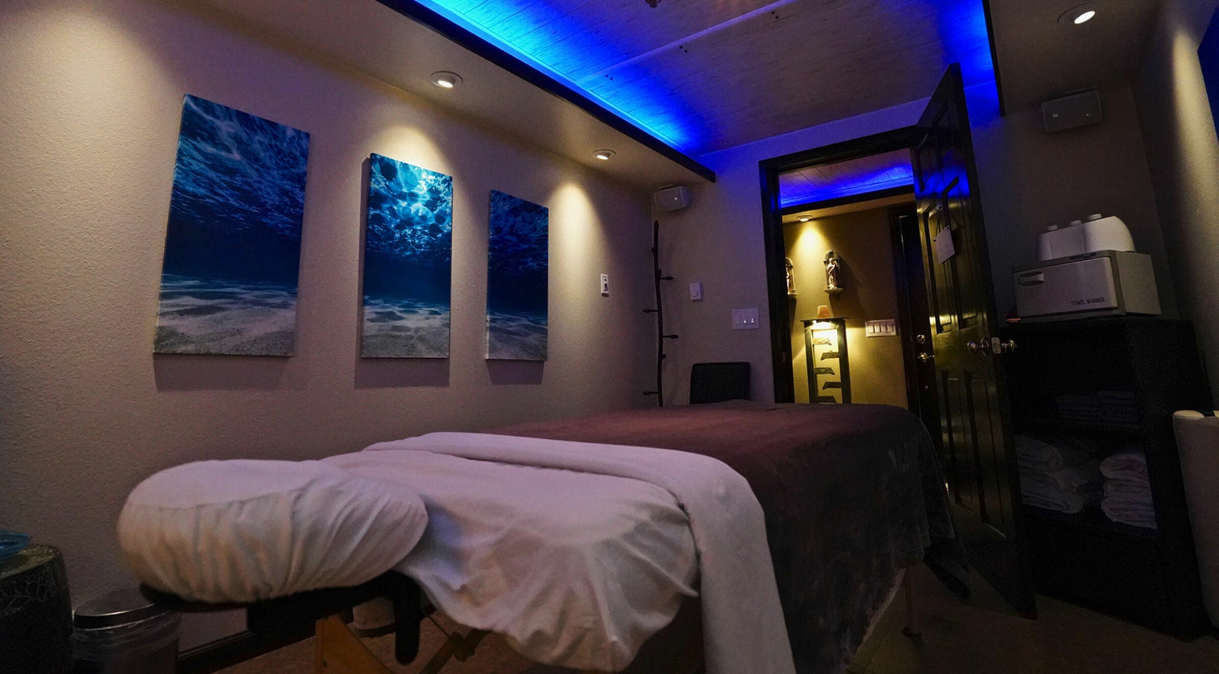 Tranquil massage room at Mt. Royal Spa in Frisco, Colorado, US with ambient lighting and ocean artwork.