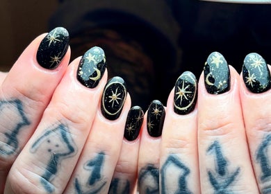 Black nails with golden celestial designs at Nics Nails, Shrewsbury, England, GB.