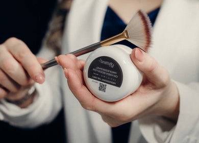 Hand holding skincare brush and jar at LUXURY SKINCARE STUDIO, Bloomington, Minnesota, US.