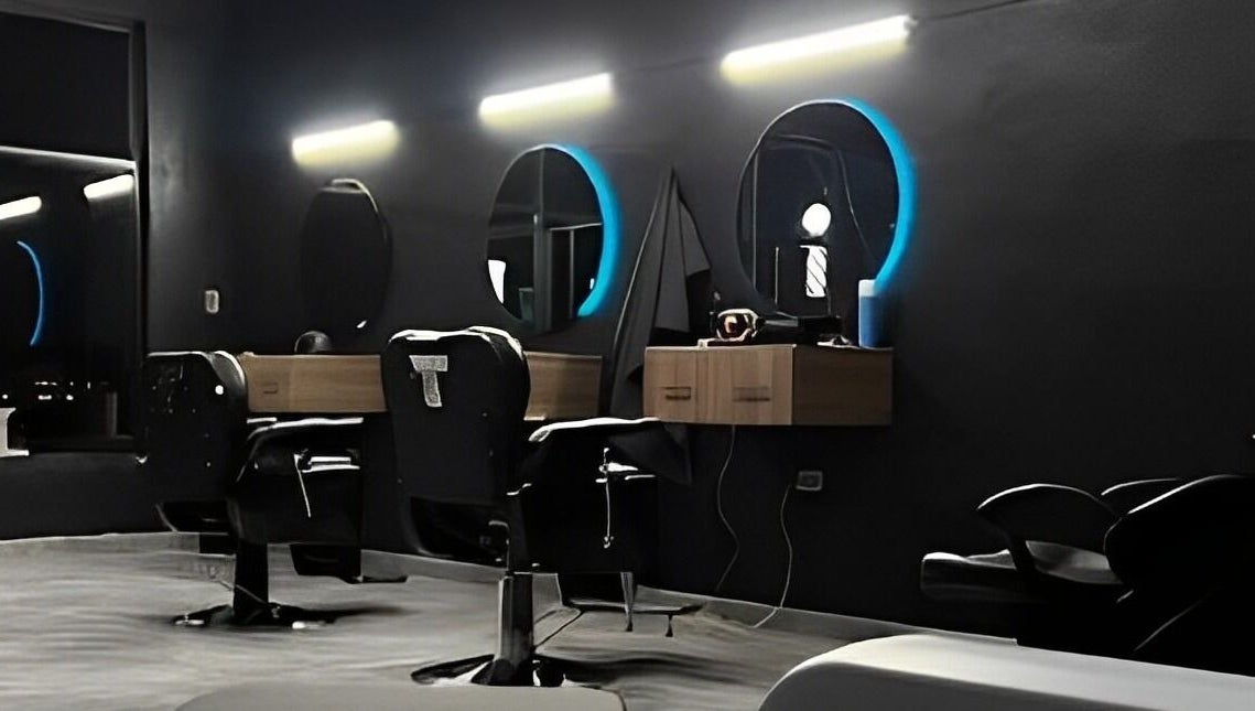 Interior moderno de Barberia Leones en Chihuahua, MX, mostrando sillas elegantes y espejos iluminados.