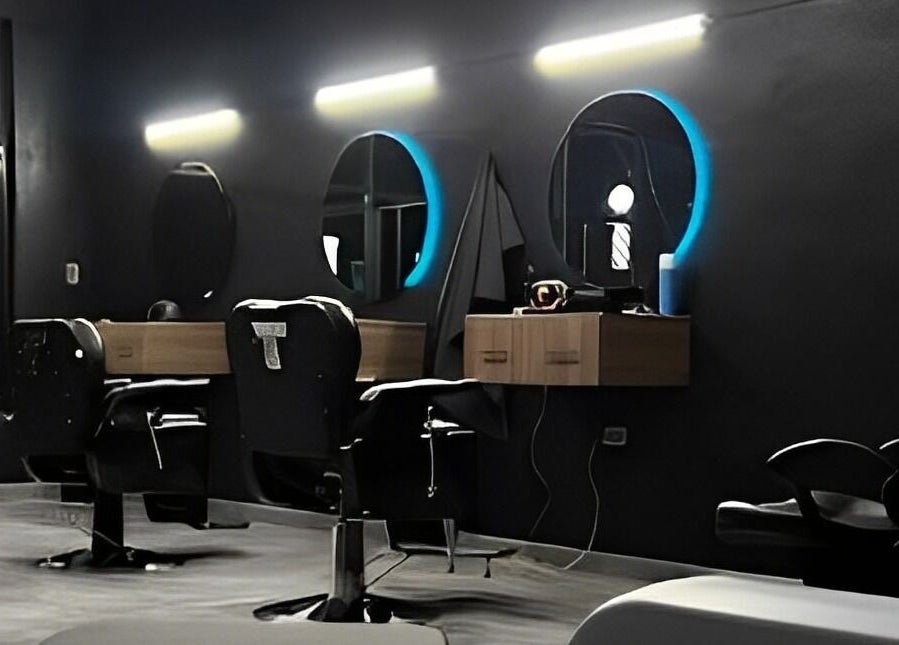 Interior moderno de Barberia Leones en Chihuahua, MX, mostrando sillas elegantes y espejos iluminados.