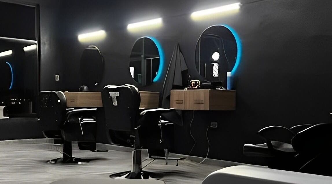 Interior moderno de Barberia Leones en Chihuahua, MX, mostrando sillas elegantes y espejos iluminados.