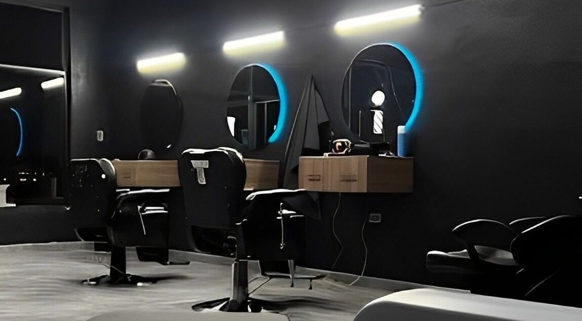 Interior moderno de Barberia Leones en Chihuahua, MX, mostrando sillas elegantes y espejos iluminados.