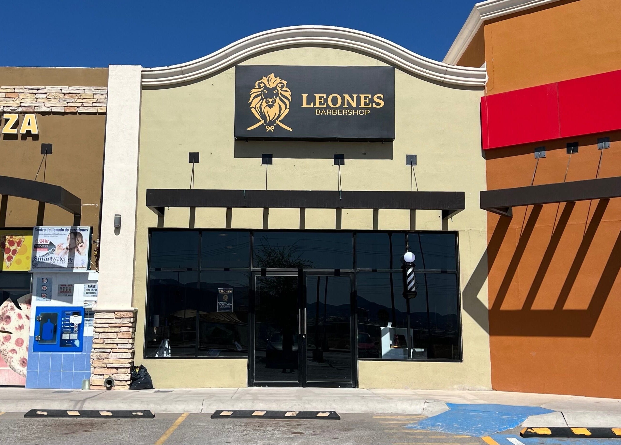 Vista frontal de Barberia leones en Chihuahua, Chihuahua, MX, con su distintivo letrero de león dorado.