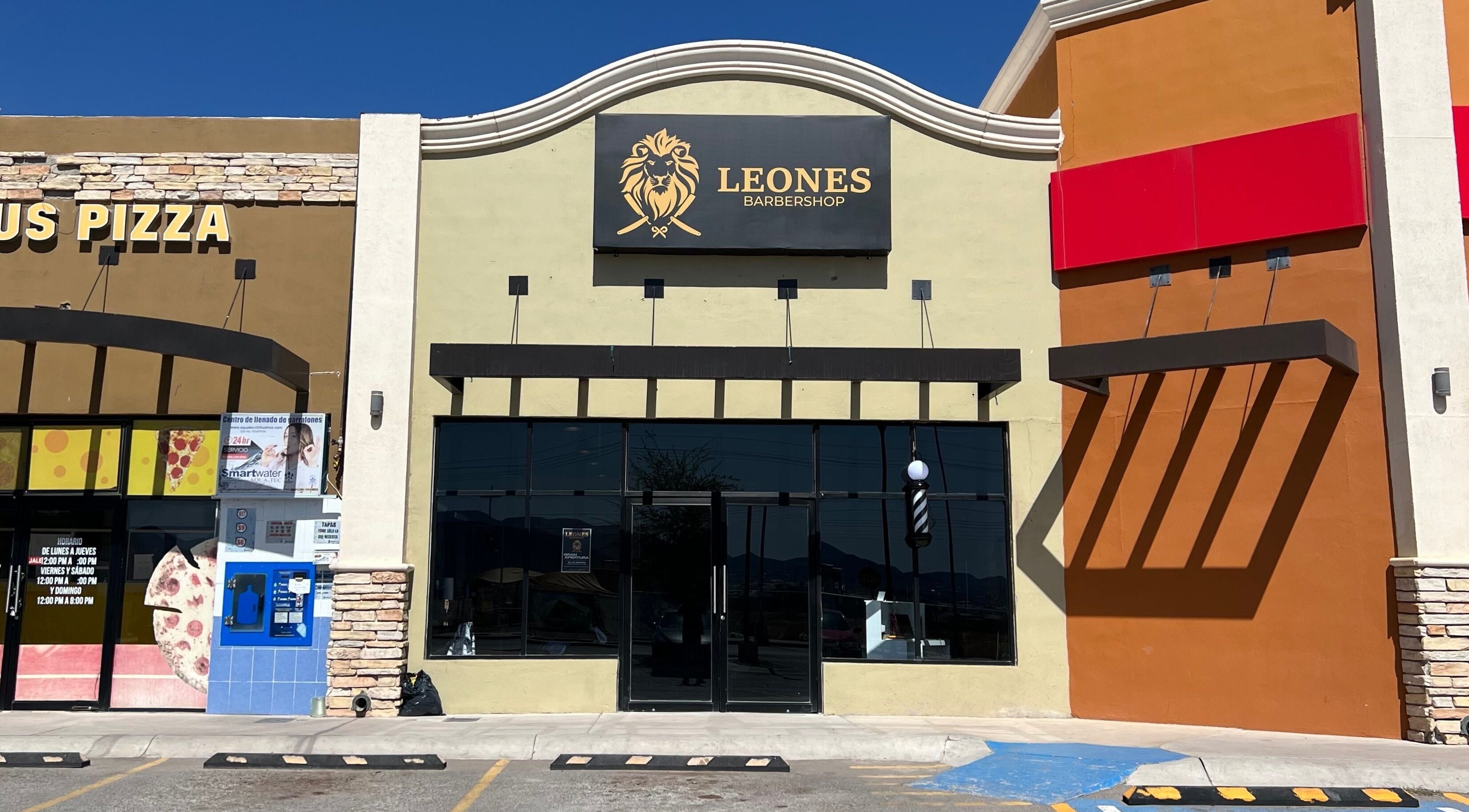 Vista frontal de Barberia leones en Chihuahua, Chihuahua, MX, con su distintivo letrero de león dorado.