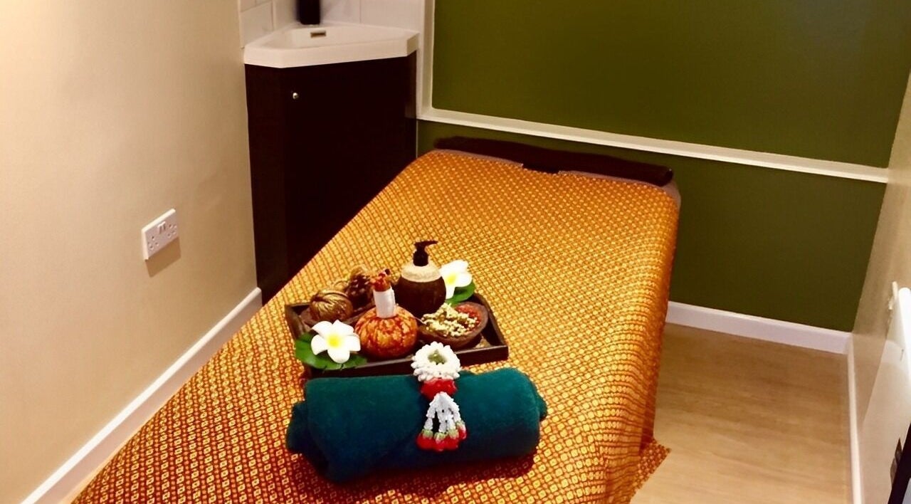 Relaxing massage room at Thai Sense Spa, London, England, GB features a cozy bed with traditional decor.