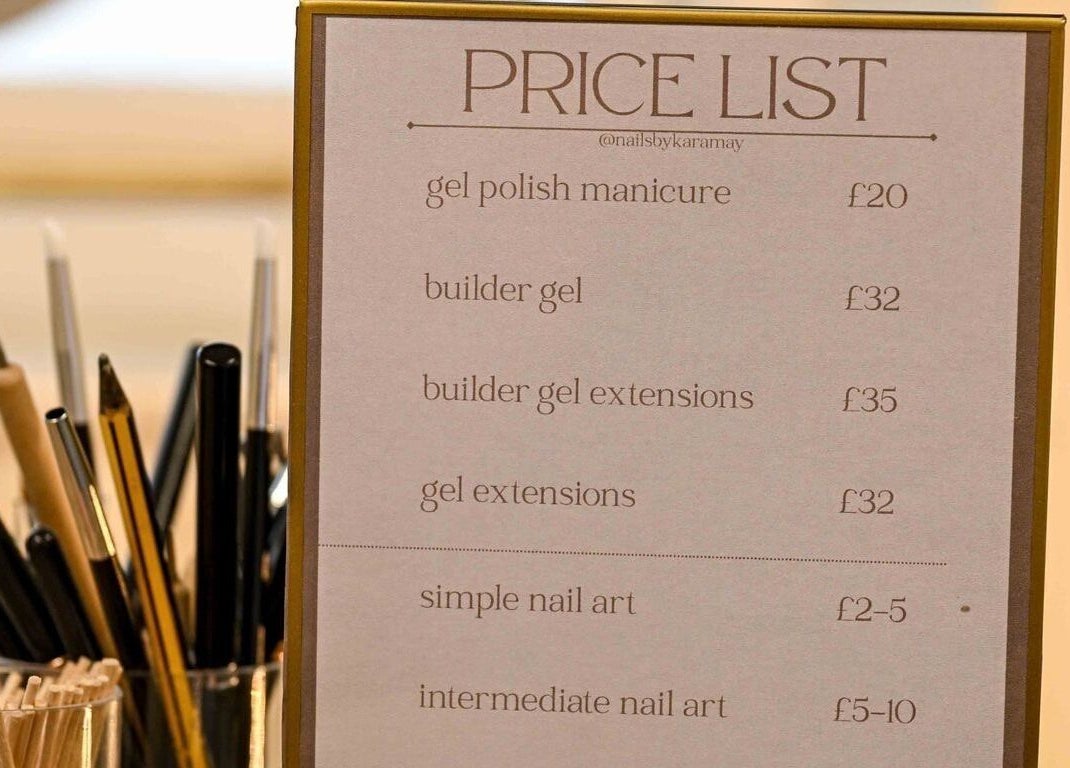 Price list for nail services at Nails by Kara May, Bridport, England, GB with pens and brushes in the background.