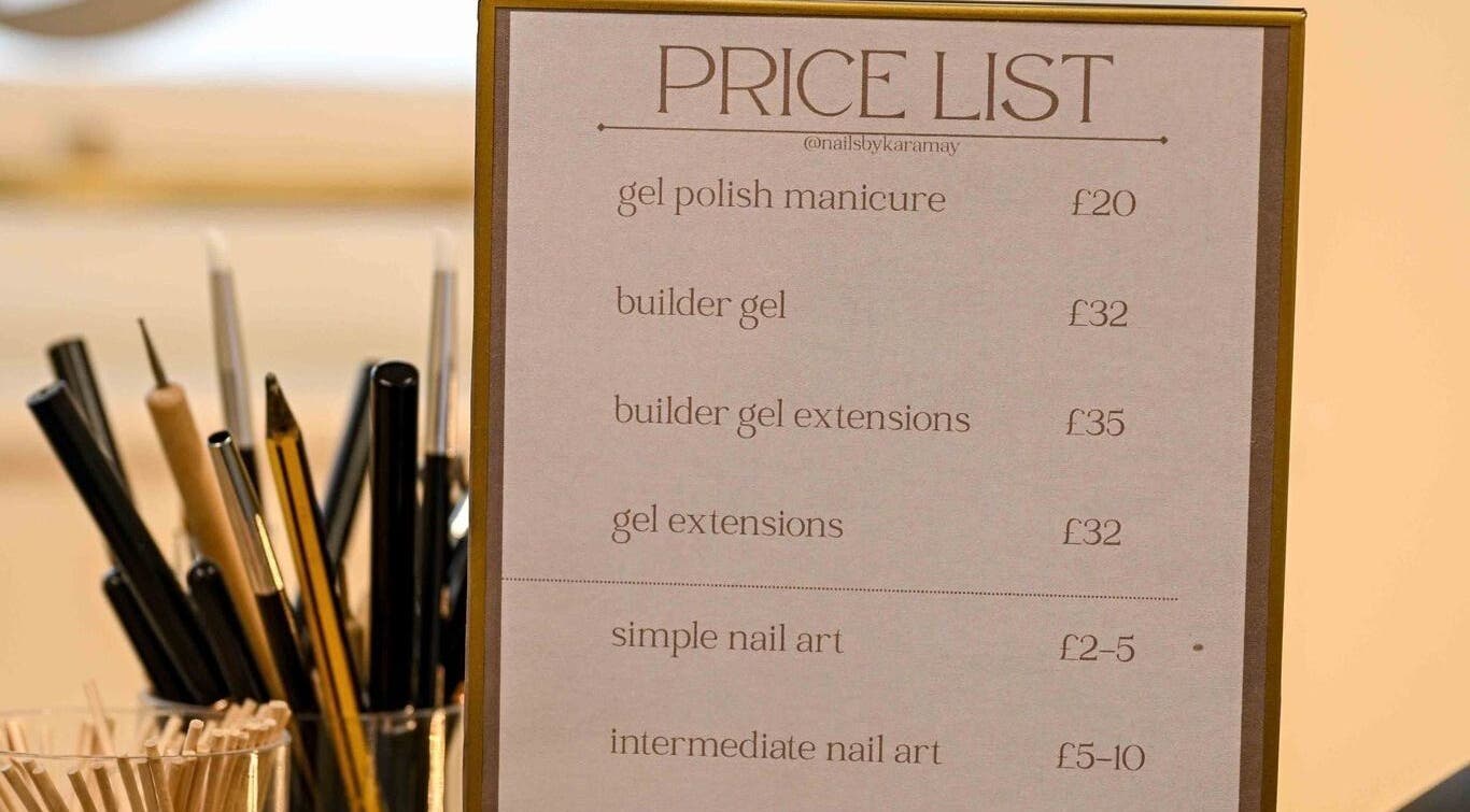 Price list for nail services at Nails by Kara May, Bridport, England, GB with pens and brushes in the background.