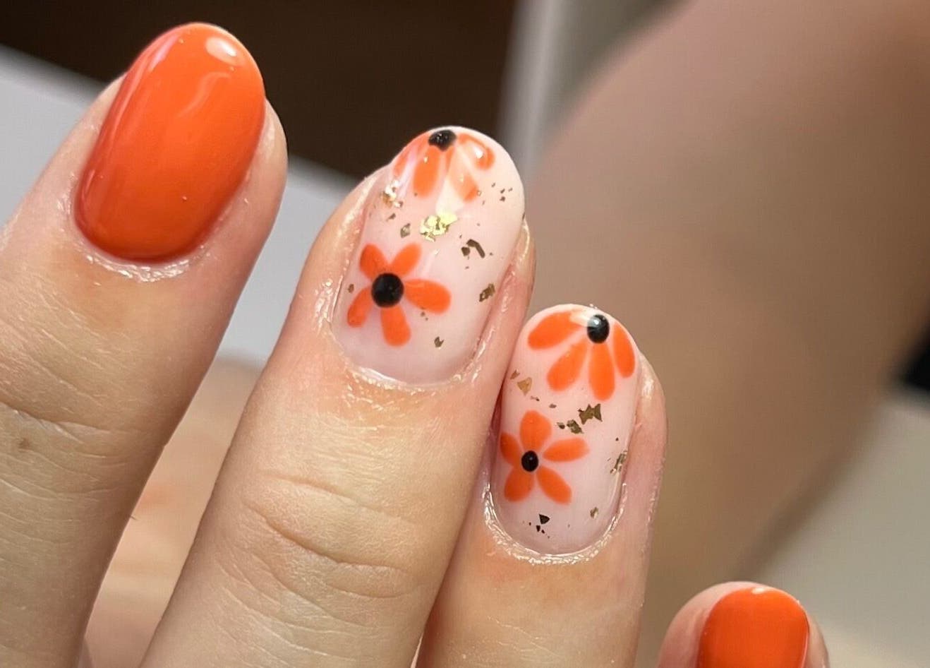 Bright floral nail art at Polished by Jasmin, Worcester, England, GB, showcasing vibrant orange designs.