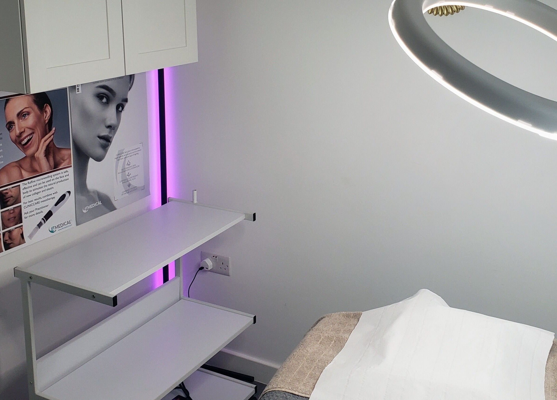 Modern treatment room at Julia Plas Skin Alsager, Stoke-on-Trent, England, GB, featuring a bright lamp and promotional posters.
