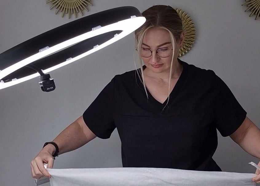 Professional at Julia Plas Skin Alsager preparing treatment room in Stoke-on-Trent, England, GB under bright lighting.