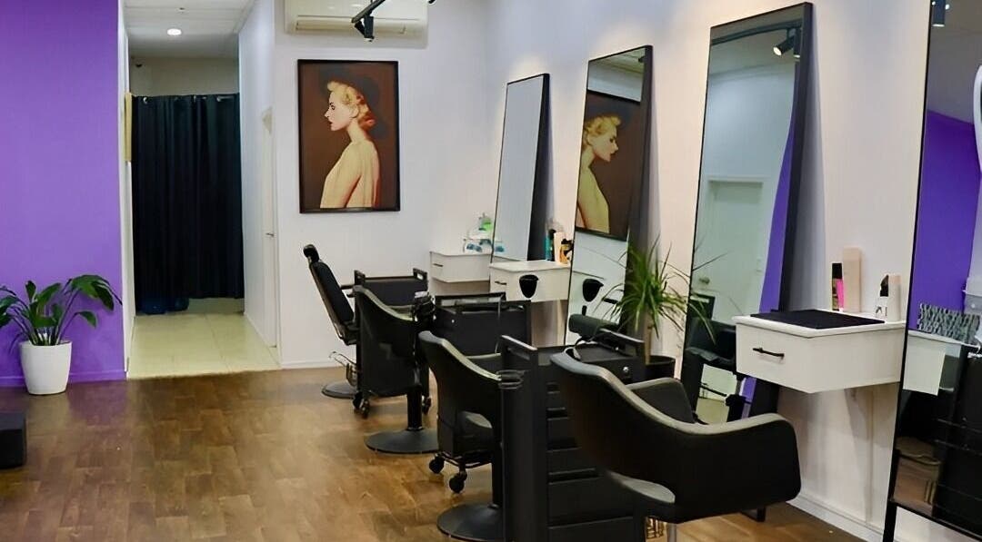 Modern salon interior at Glam Plus Hair & Beauty Salon, Auckland, NZ, featuring stylish chairs and wall art.