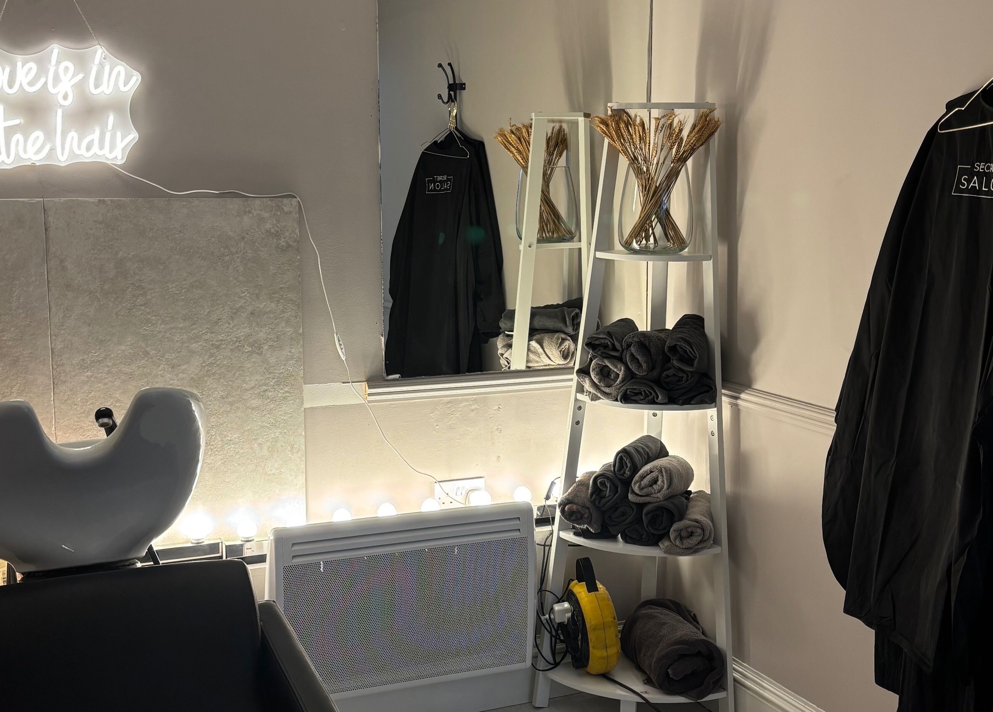 Cozy interior of Secret Salon in Pucklechurch, England, GB with chic decor and neon sign.