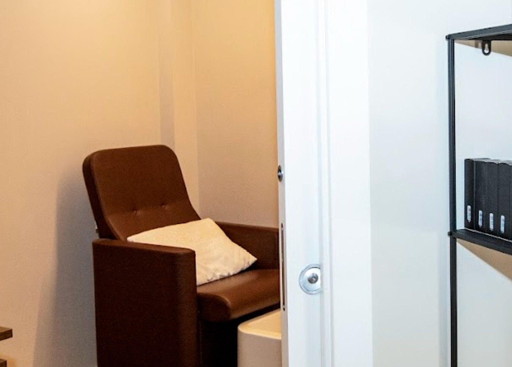 Accogliente area relax presso Beauty Charme, Botticino, Lombardia, IT con poltrona marrone e scaffale nero.