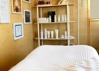 Cozy spa room at Bloom Boutique Beauty in Dunedin, Otago, NZ, showcasing skincare products on a wooden shelf.