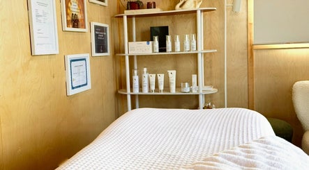 Cozy spa room at Bloom Boutique Beauty in Dunedin, Otago, NZ, showcasing skincare products on a wooden shelf.