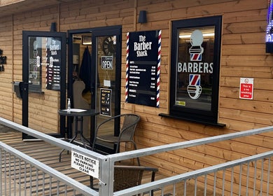 Front view of The Barber Shack in Saint Martin's, England, GB, showcasing its wooden exterior and signage.