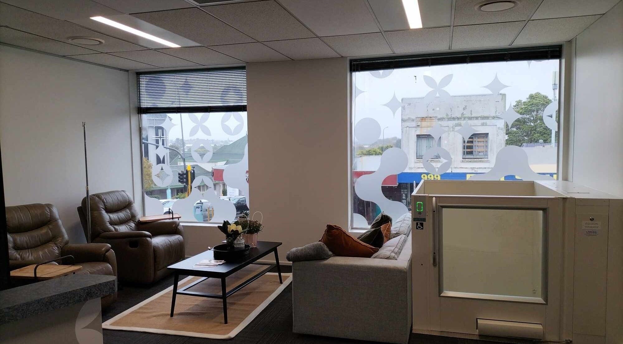 Relaxing lounge with leather chairs at Viva Clinics, Auckland, NZ, featuring a stylish window view.