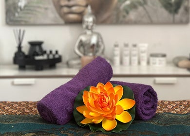 Relaxing therapy setup at Thai Massage Greenock, Greenock, Scotland, GB, with purple towels and lotus flower.