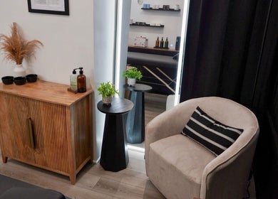 Cozy seating and decor at Kendra, Downey, California, US, featuring a plush chair and wooden cabinet.