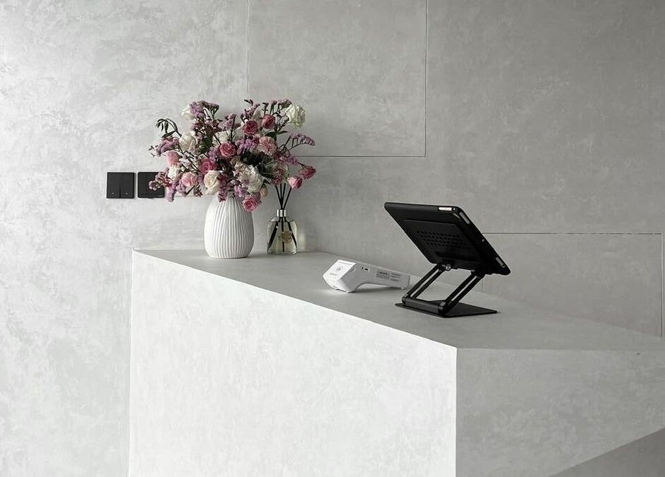 Kev Lounge Barber's sleek concrete reception in Umm Al Quwain, AE, adorned with floral decor and modern tech.