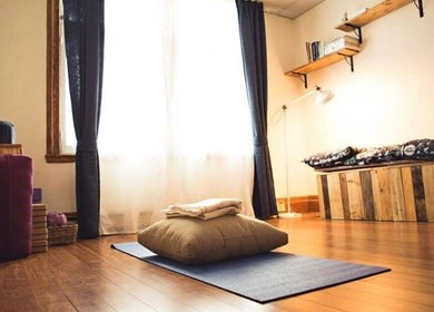 Salle de détente chez Amparo ૐ Voice & Massage & Bioenergetics à Montréal, Québec, CA, avec tapis et coussins.