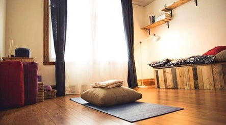 Salle de détente chez Amparo ૐ Voice & Massage & Bioenergetics à Montréal, Québec, CA, avec tapis et coussins.