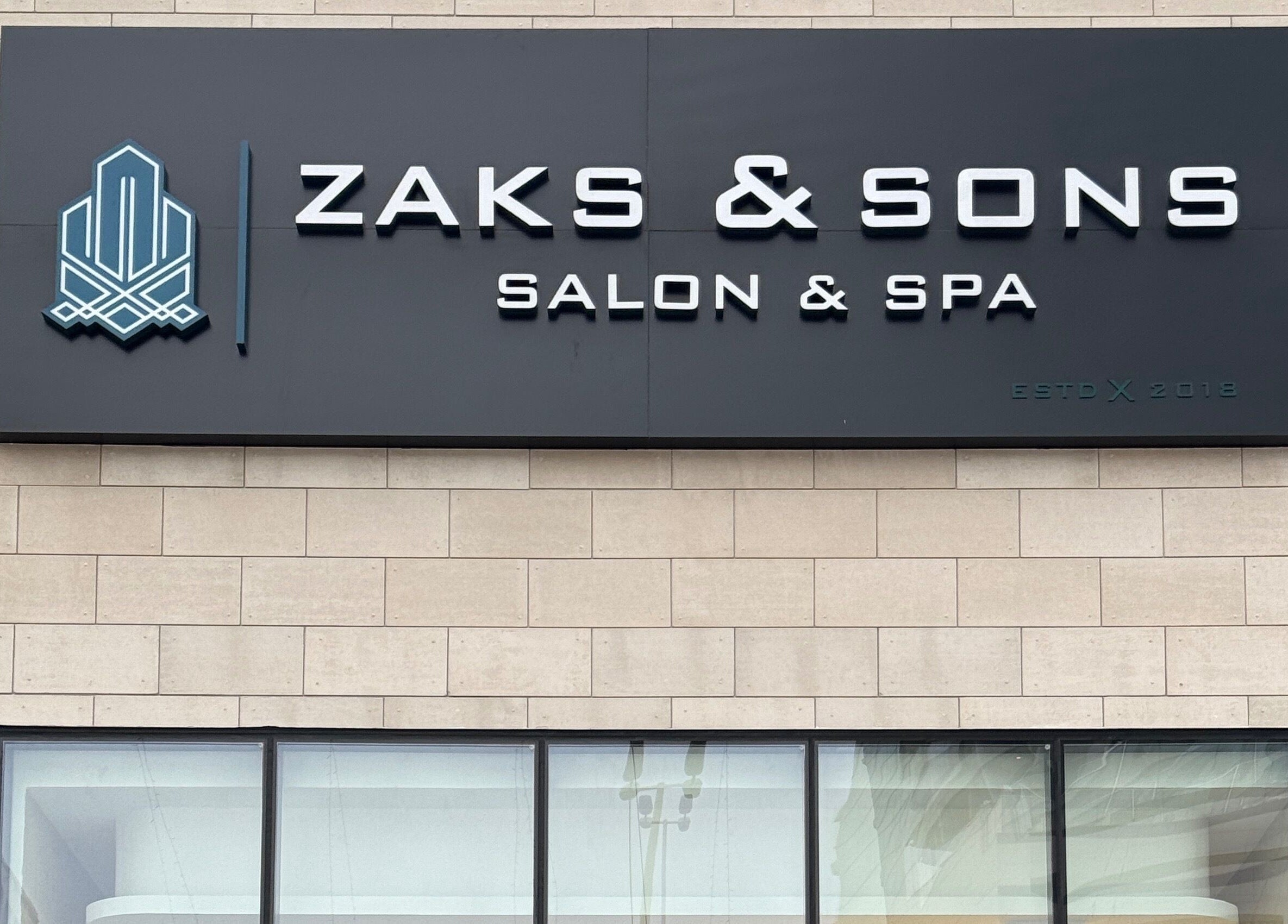 Signage of Zaks and Sons Salon and Spa in Manama, Capital Governorate, BH on a stylish stone facade.