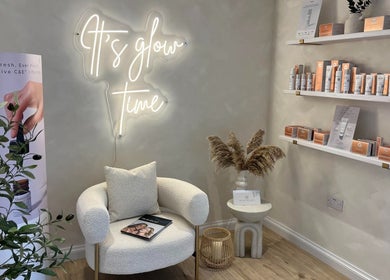 Cozy corner at The Glow Skin Clinic, Caddington, Luton with neon sign and skincare products on shelves.