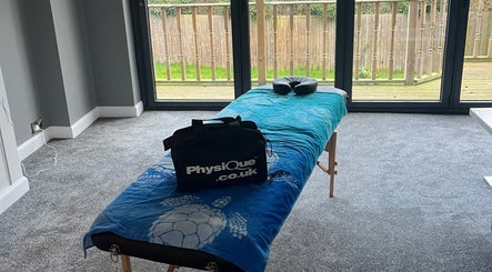 Massage table in serene room at Caitlin May Massage, Lichfield, England, GB with large windows and relaxing decor.