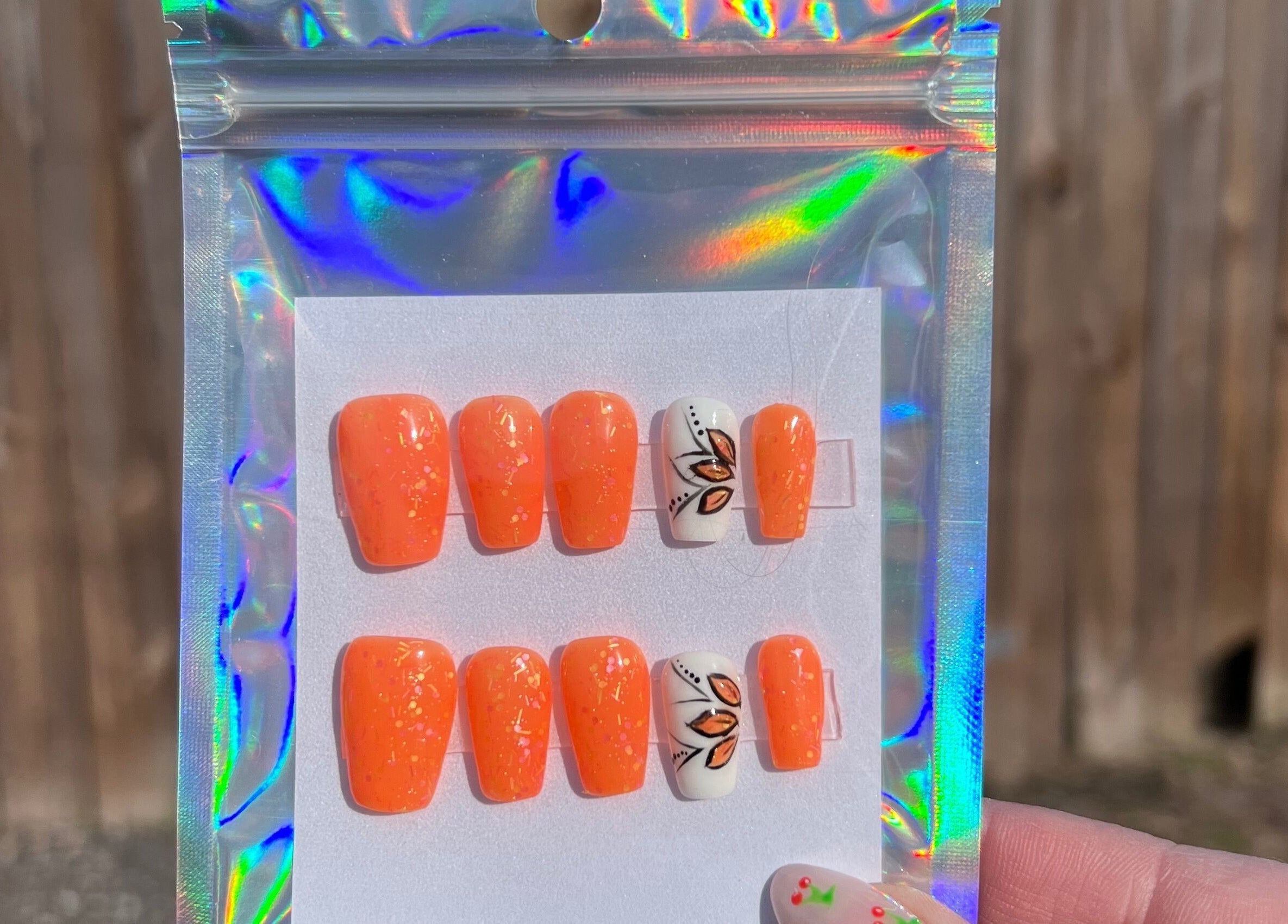 Vibrant orange nail set with floral detail from Rook and Raven Nail Co., Saltsburg, Pennsylvania, US.