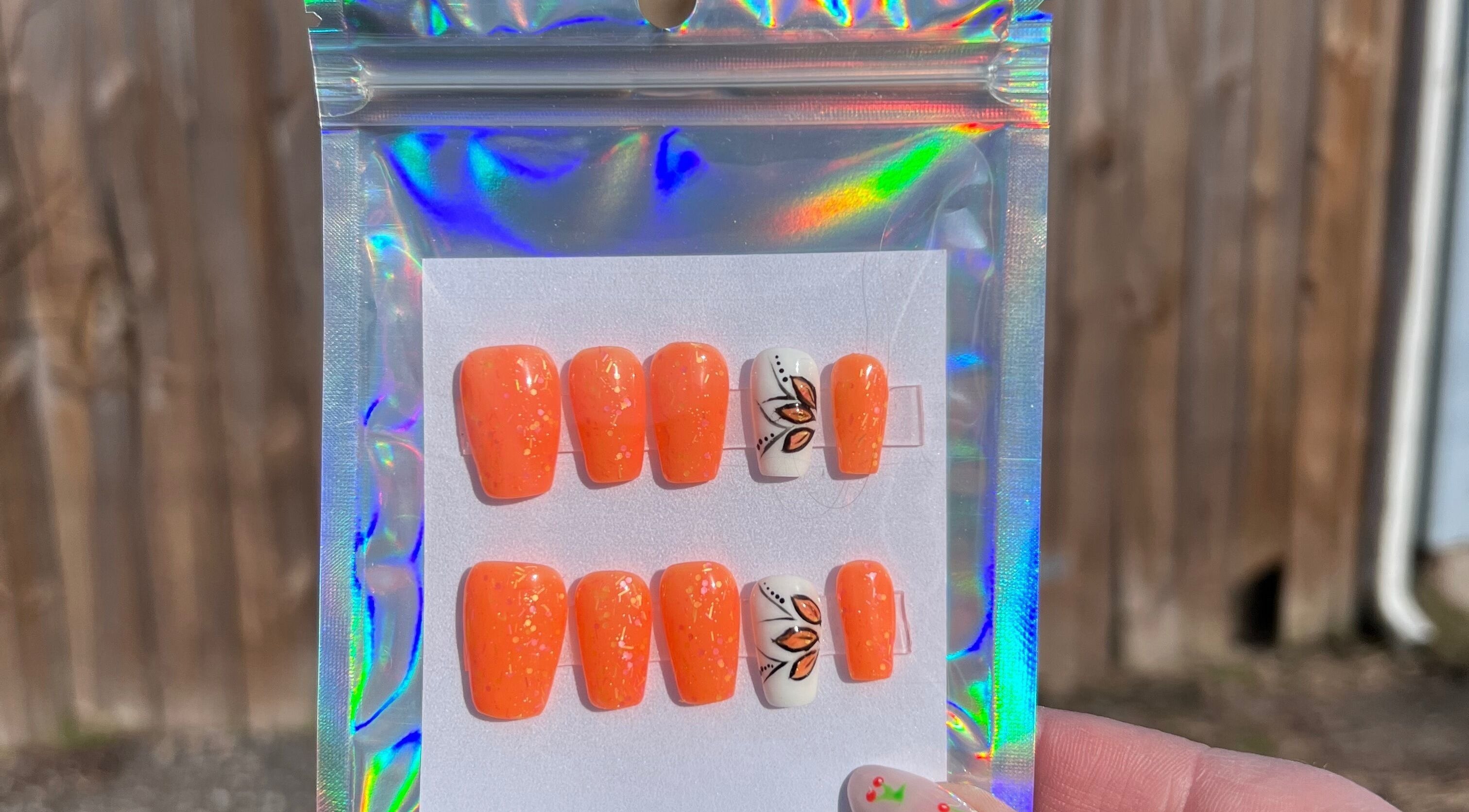 Vibrant orange nail set with floral detail from Rook and Raven Nail Co., Saltsburg, Pennsylvania, US.