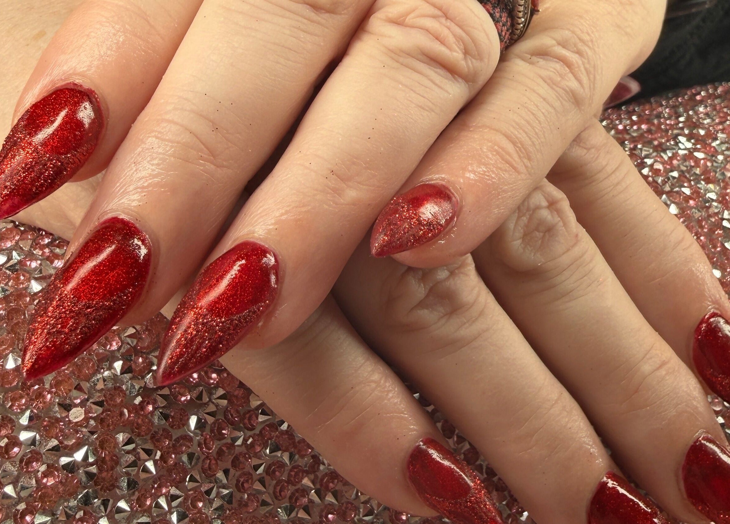Elegant red nails with glitter finish at Rook and Raven Nail Co., Saltsburg, Pennsylvania, US.