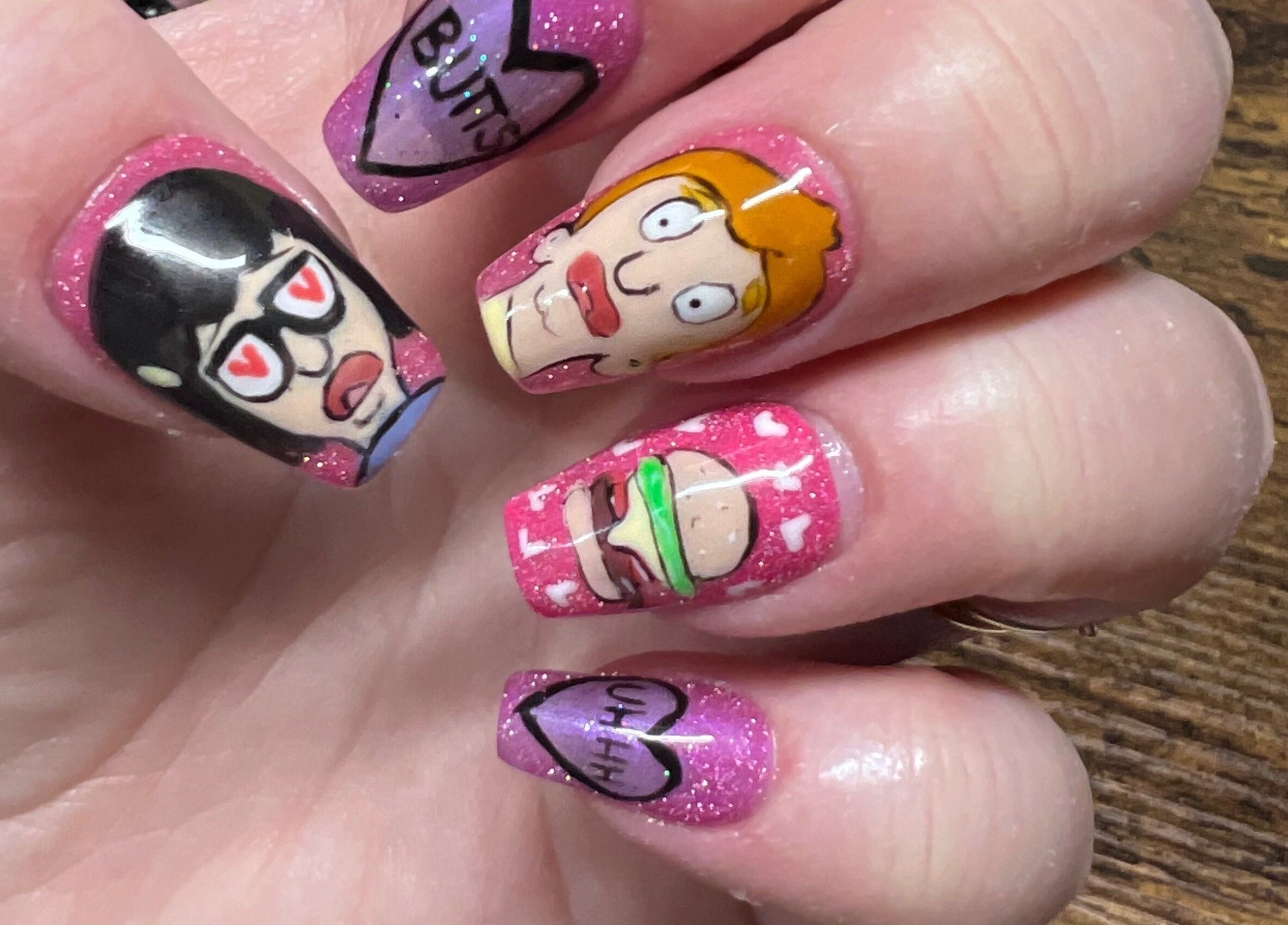 Cartoon-themed nail art from Rook and Raven Nail Co. in Saltsburg, Pennsylvania, US on pink glitter background.