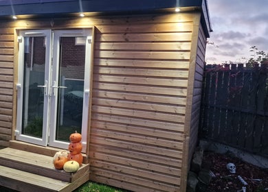 Wooden cabin entrance at J'adore Beauty Rooms, Normanton, England, GB, decorated with pumpkins and lights.