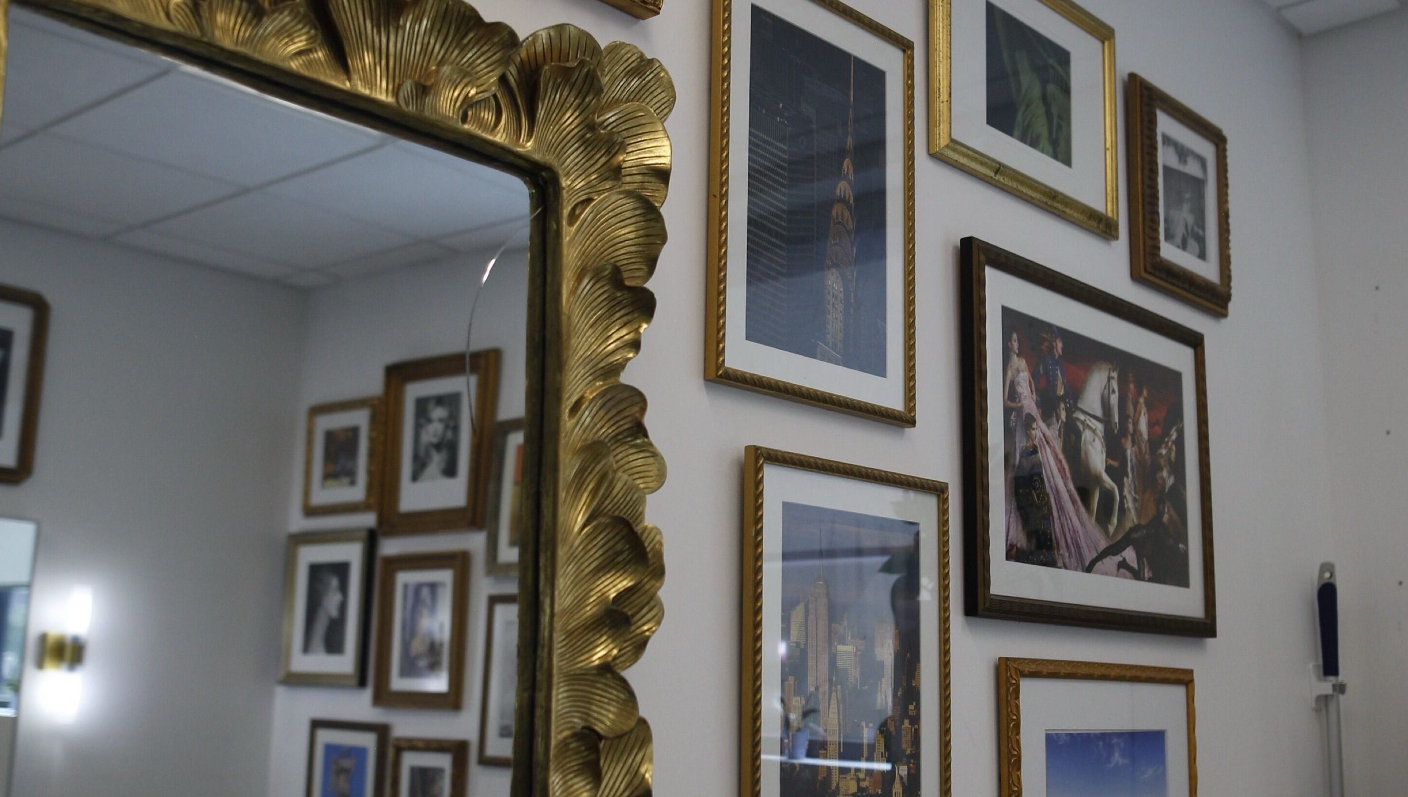 Elegant wall with framed art and ornate mirror at Intention Hair Studio, Dallas, Texas, US.