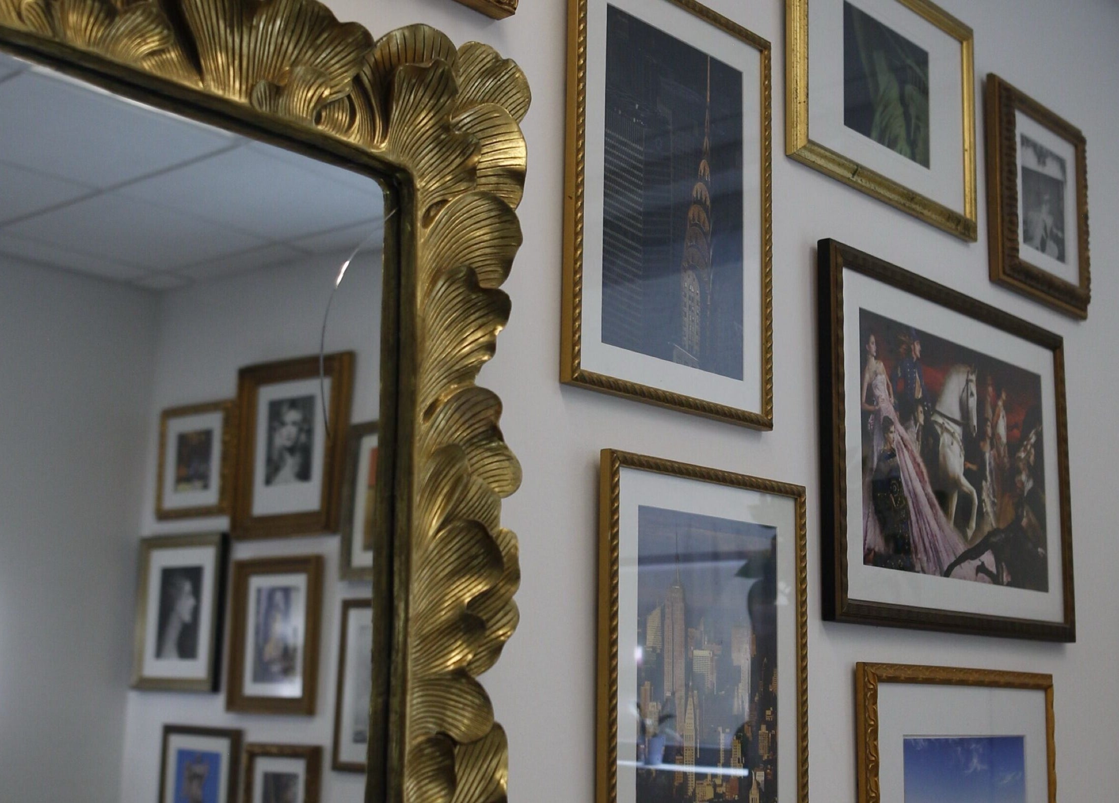 Elegant wall with framed art and ornate mirror at Intention Hair Studio, Dallas, Texas, US.
