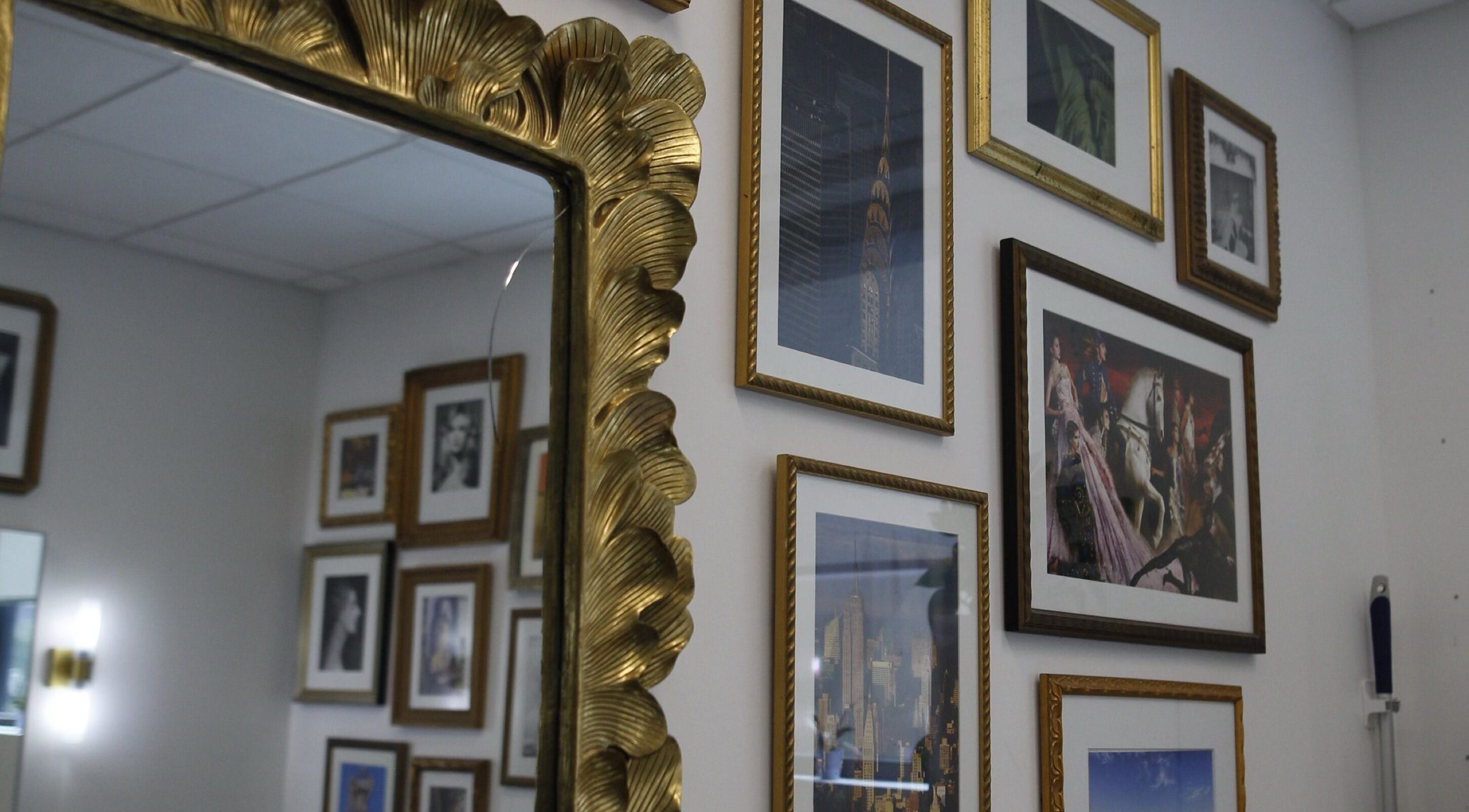 Elegant wall with framed art and ornate mirror at Intention Hair Studio, Dallas, Texas, US.