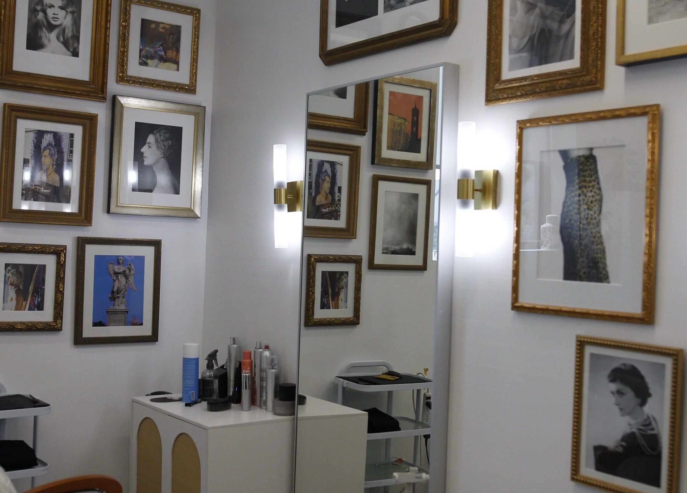 Art-decorated wall at Intention Hair Studio in Dallas, Texas, US, showcasing framed portraits and elegant mirrors.
