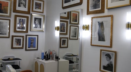 Art-decorated wall at Intention Hair Studio in Dallas, Texas, US, showcasing framed portraits and elegant mirrors.